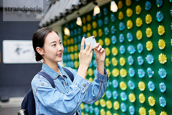 Eine Frau fotografiert eine Wand mit Papierblumen