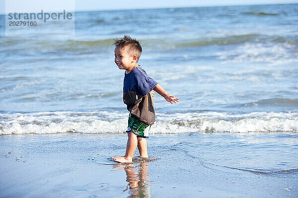 Ein kleiner Junge  der am Strand spaziert
