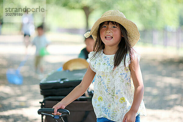Ein kleines Mädchen mit Hut und Karren