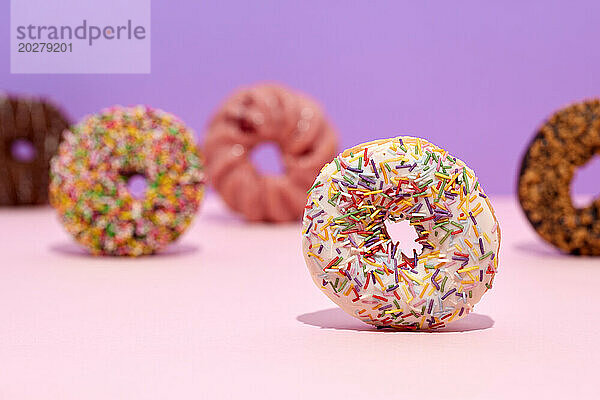 Eine Gruppe Donuts mit Streuseln auf rosa Hintergrund