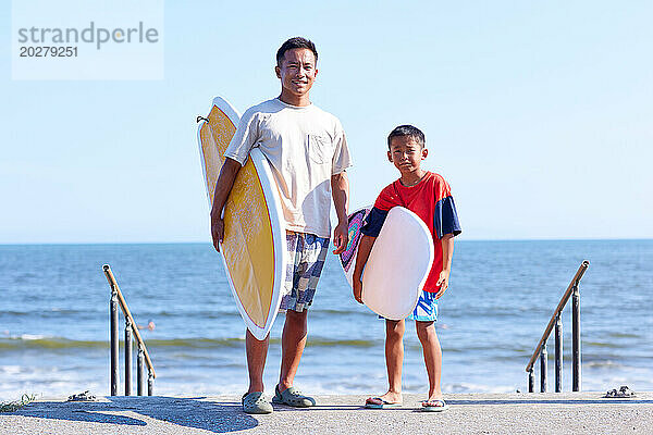 Familie mit Surfbrettern am Strand