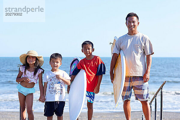 Familie mit Surfbrettern am Strand