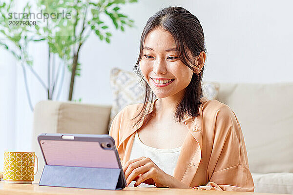 Asiatische Frau benutzt Tablet-Computer im Wohnzimmer