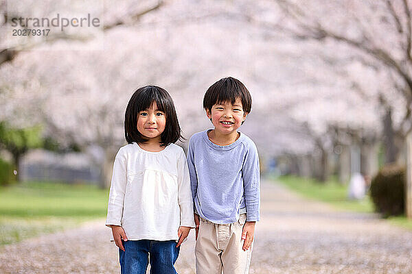 Zwei kleine Kinder stehen vor einem Baum