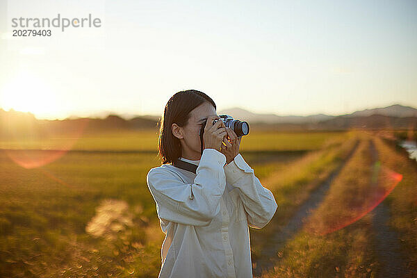 Eine Frau fotografiert ein Feld bei Sonnenuntergang