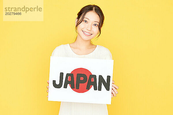 Eine schöne asiatische Frau hält ein Schild mit der Aufschrift Japan