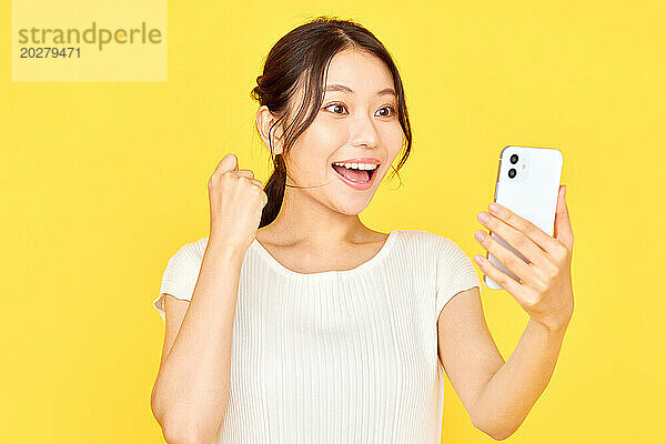Asiatische Frau macht Selfie mit Smartphone auf gelbem Hintergrund