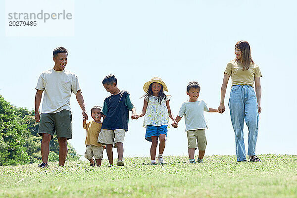 Eine Familie geht auf einer Wiese spazieren