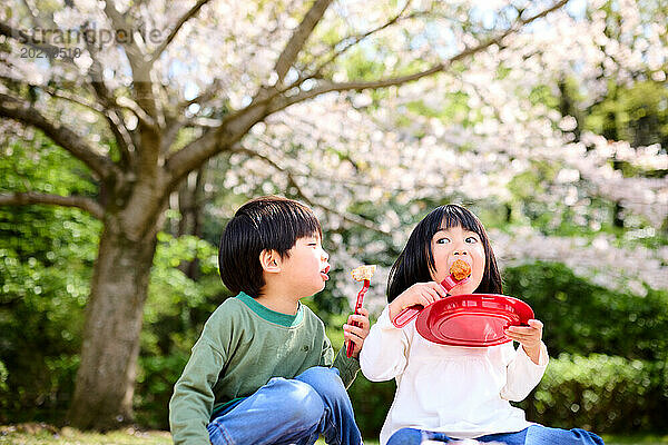 Zwei Kinder essen im Park