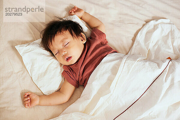 Asiatisches Baby schläft im Bett