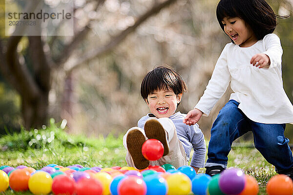 Zwei Kinder spielen mit Bällen im Gras