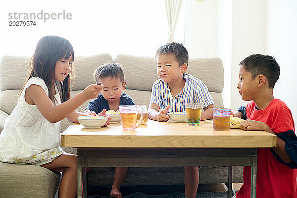 Kinder sitzen an einem Tisch und essen