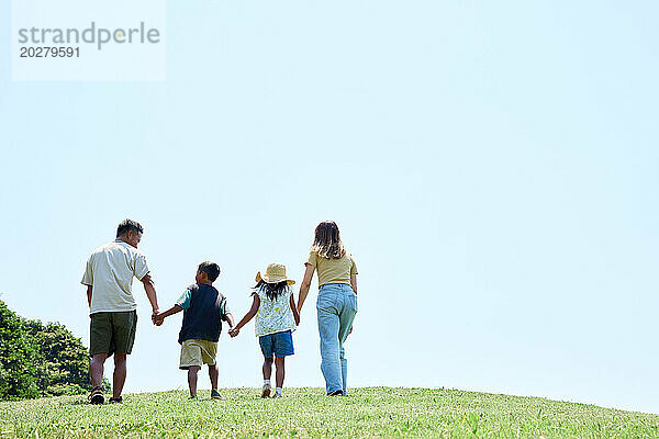 Eine Familie geht auf einem grasbewachsenen Hügel spazieren