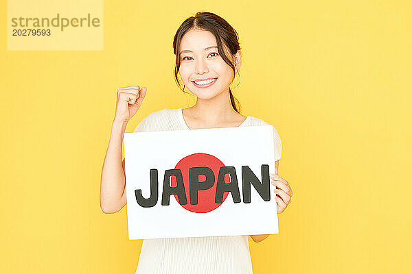 Japanerin hält ein Schild mit der Aufschrift „Japan“ hoch