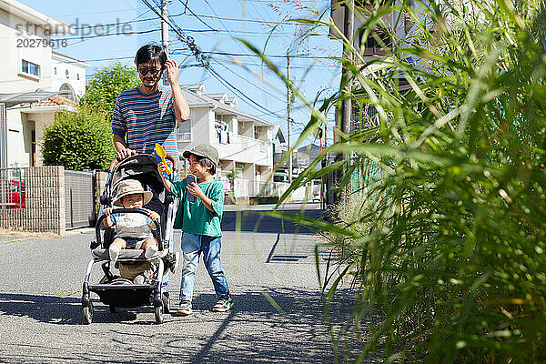 Ein Mann und zwei Kinder gehen eine Straße entlang