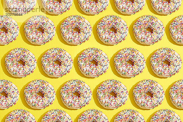 Ein Muster aus Donuts mit Streuseln auf gelbem Hintergrund