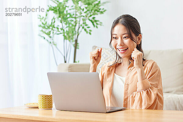 Asiatische Frau benutzt Laptop im Wohnzimmer