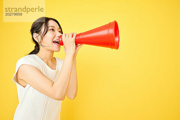 Asiatische Frau schreit in ein rotes Megafon