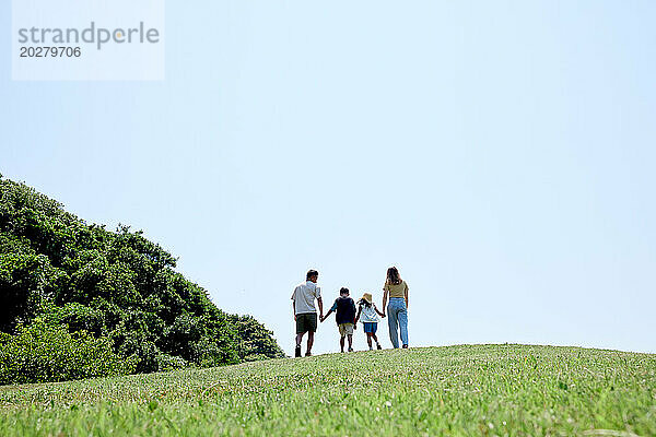 Eine Familie geht auf einem grasbewachsenen Hügel spazieren