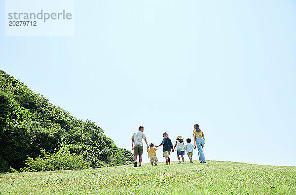 Eine Familie geht auf einem grasbewachsenen Hügel spazieren