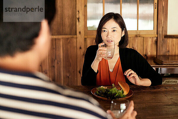 Eine Frau sitzt mit einem Teller mit Essen an einem Tisch