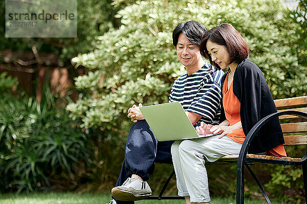 Asiatisches Paar benutzt Laptop im Garten