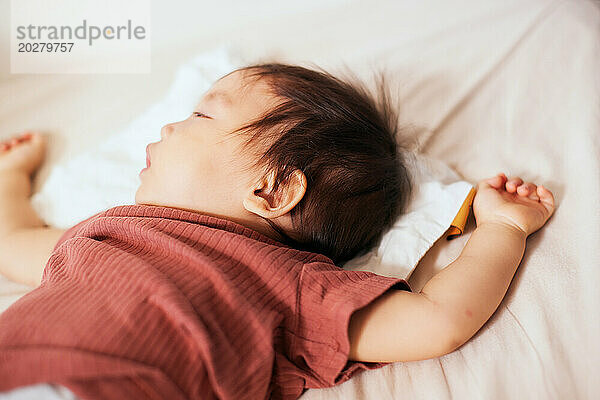 Asiatisches Baby schläft im Bett