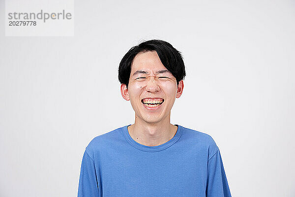 Ein Mann lacht und lächelt vor einem weißen Hintergrund