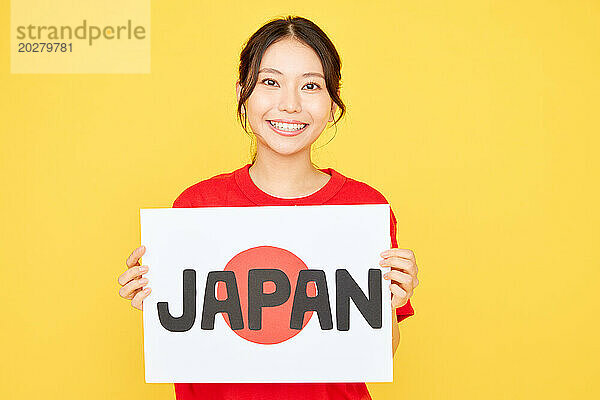 Asiatische Frau hält Japan-Schild auf gelbem Hintergrund