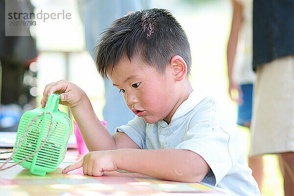 Ein kleiner Junge spielt mit einem grünen Plastikspielzeug
