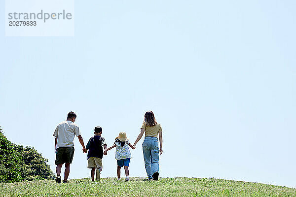 Eine Familie geht auf einem grasbewachsenen Hügel spazieren