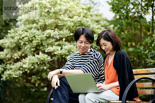 Asiatisches Paar benutzt Laptop im Garten