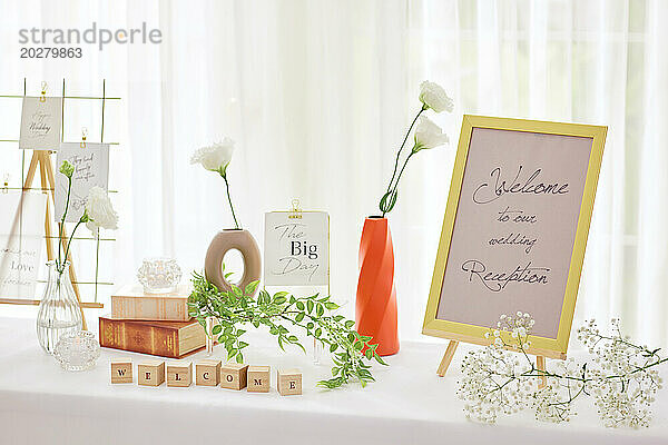 Hochzeitstisch mit Blumen und einem Willkommensschild
