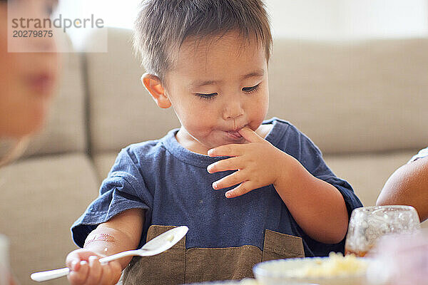 Kind sitzt an einem Tisch und isst Essen