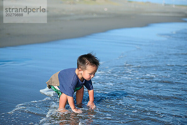 Ein kleiner Junge  der am Meer spielt