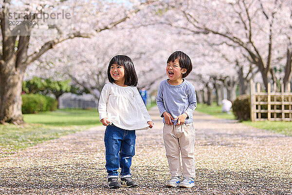 Zwei kleine Kinder stehen vor einem Baum