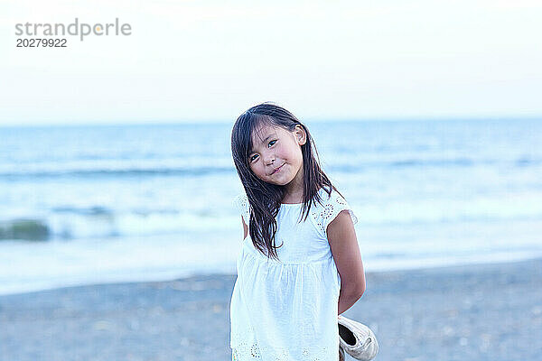 Ein kleines Mädchen steht am Strand