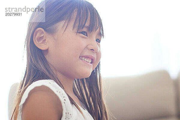Ein kleines Mädchen lächelt  während es auf einer Couch sitzt