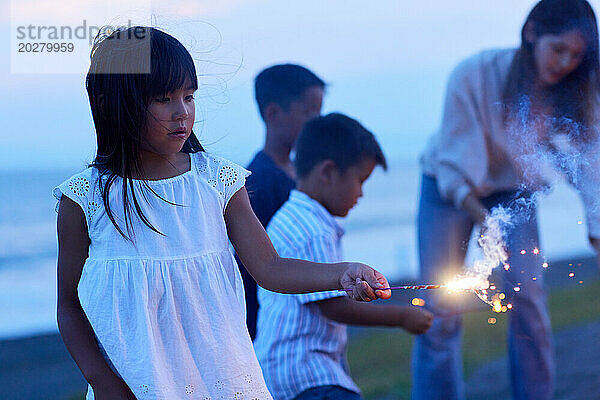 Ein junges Mädchen hält eine Wunderkerze vor einer Gruppe von Kindern