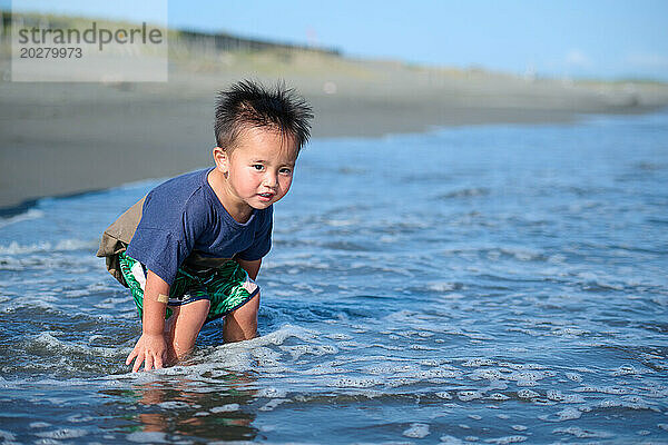Ein kleiner Junge  der am Meer spielt