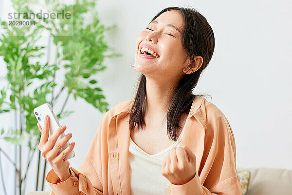Asiatische Frau lacht  während sie ihr Handy benutzt