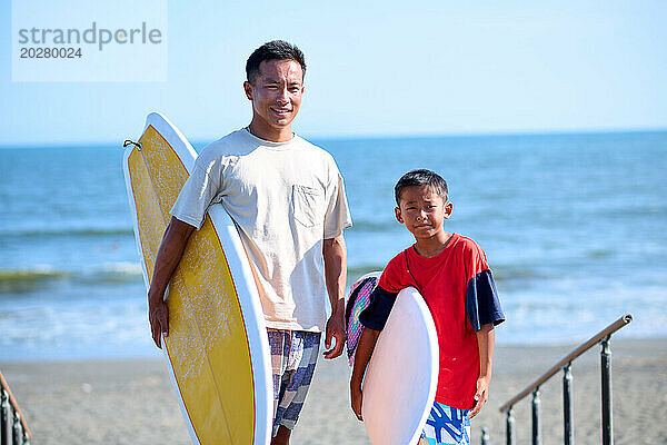 Familie mit Surfbrettern am Strand