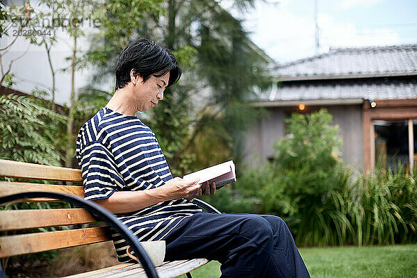 Ein Mann sitzt auf einer Bank und liest ein Buch