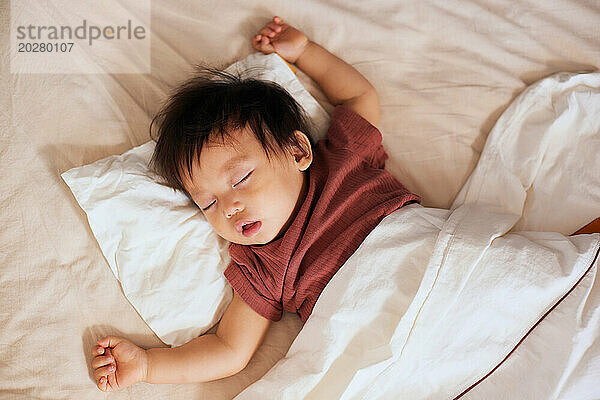 Asiatisches Baby schläft im Bett