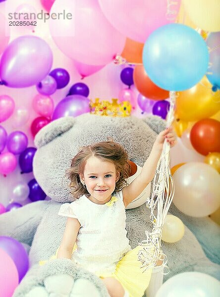 Fröhliches kleines Mädchen posiert und hält ein Bündel Luftballons