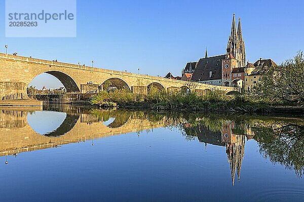 Kirche und Brücke spiegeln sich in Fluss  Abendlicht  sonnig  idyllisch  Regensburger Dom und steinerne Brücke  Regensburg  Donau  Bayern  Deutschland  Europa
