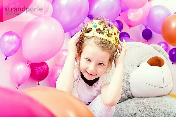 Porträt eines lustigen kleinen Mädchens  das eine Krone im Atelier anprobiert