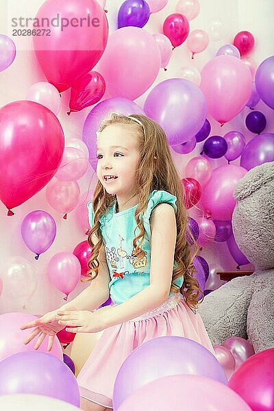 Studioaufnahme eines süßen kleinen Mädchens  das unter Luftballons spielt