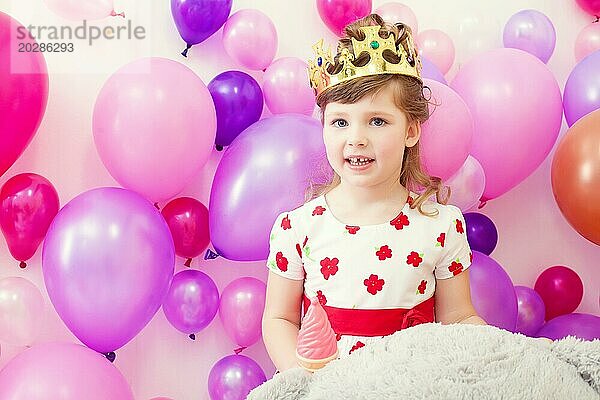 Nettes kleines Mädchen posiert in Krone auf Luftballons Hintergrund