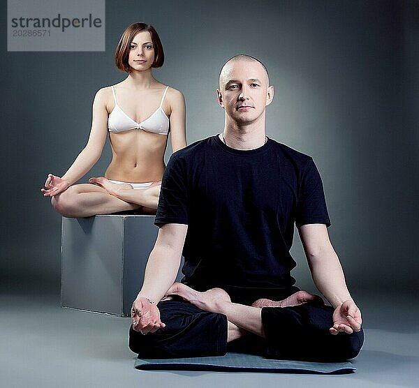 Studioaufnahme von meditierenden Yogatrainern  vor grauem Hintergrund